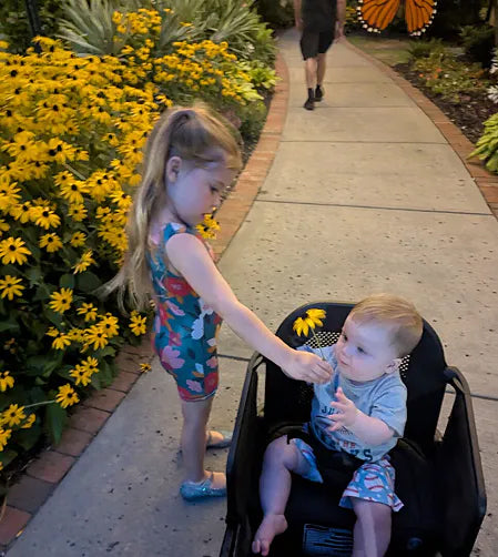Older sister checking on her baby brother during a flower garden outing