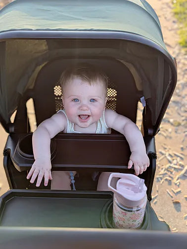 Baby riding in the Waggle on a shaded path