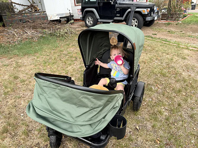 Toddler relaxing with a drink in a green Waggle wagon