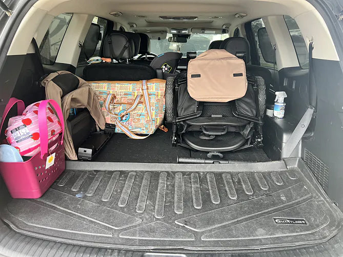 Folded brown Waggle wagon fitting beside family gear in the back of an SUV