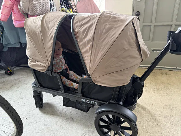 Baby sitting beneath the extended canopies of a brown Waggle wagon