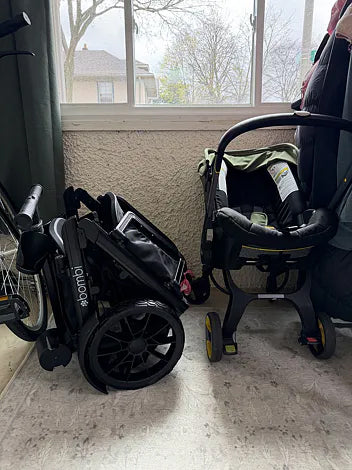 Folded black Waggle wagon stored beside an infant car seat
