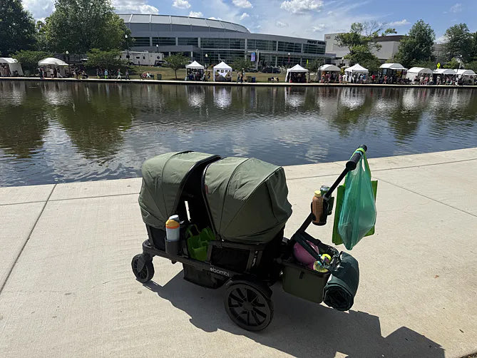 Loaded green Waggle wagon parked beside a pond at an outdoor festival