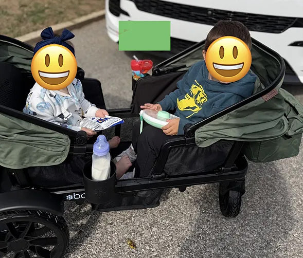 Two children sitting across from each other in a green Waggle wagon